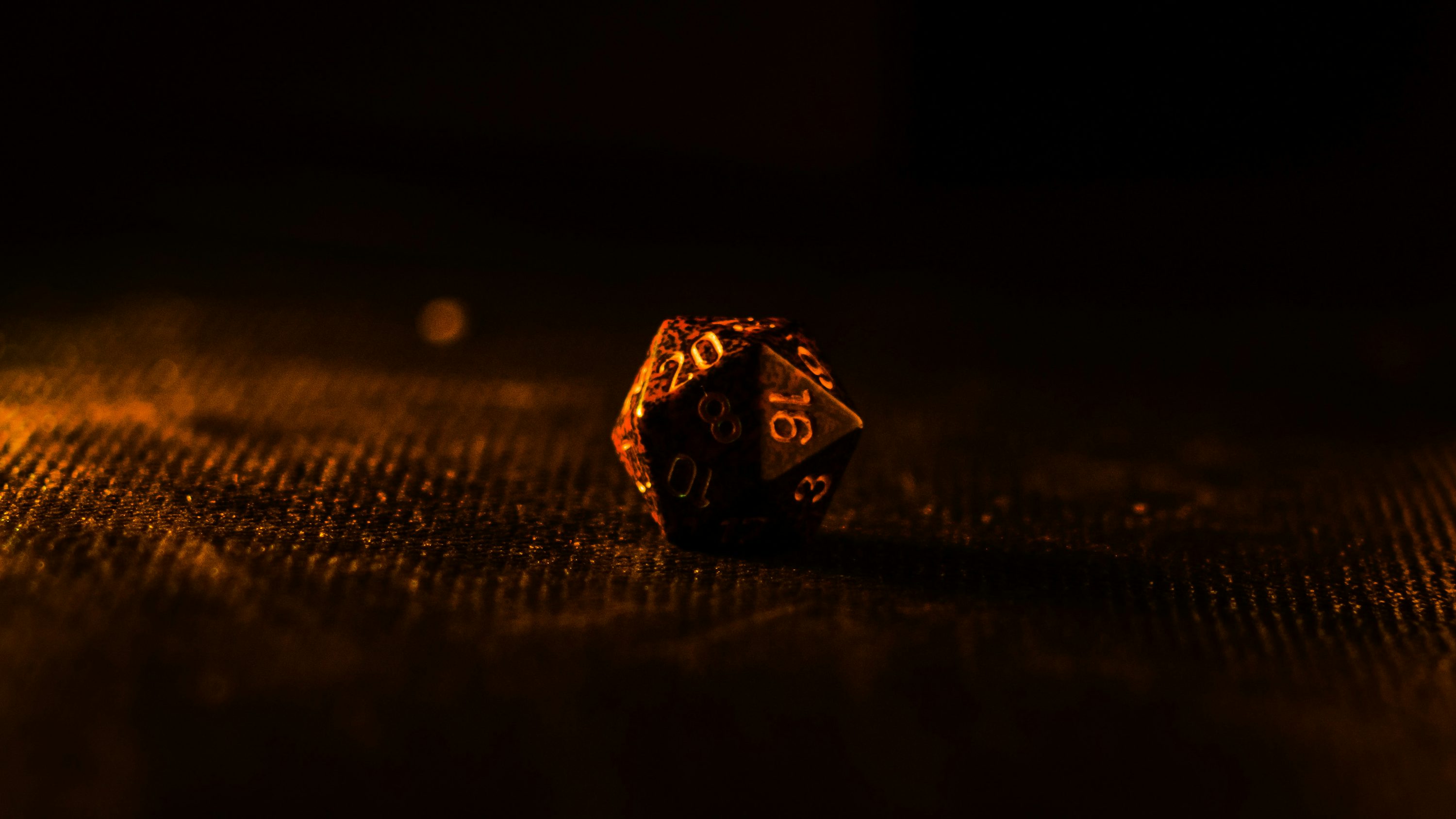 A real twenty-sided die glowing in warm amber light on a brown tabletop